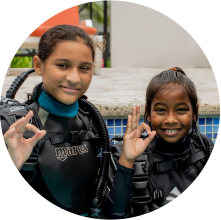 Two girls in scuba gear posing for a picture while scuba diving in Grenada.